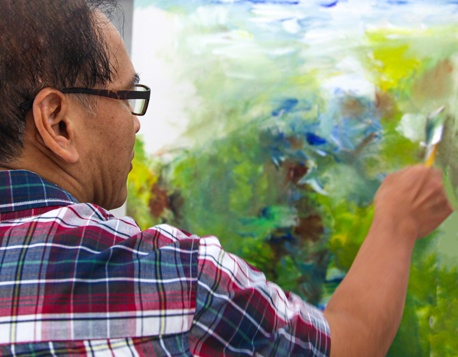 This image features an artist applying shades of white to his abstract green painting.